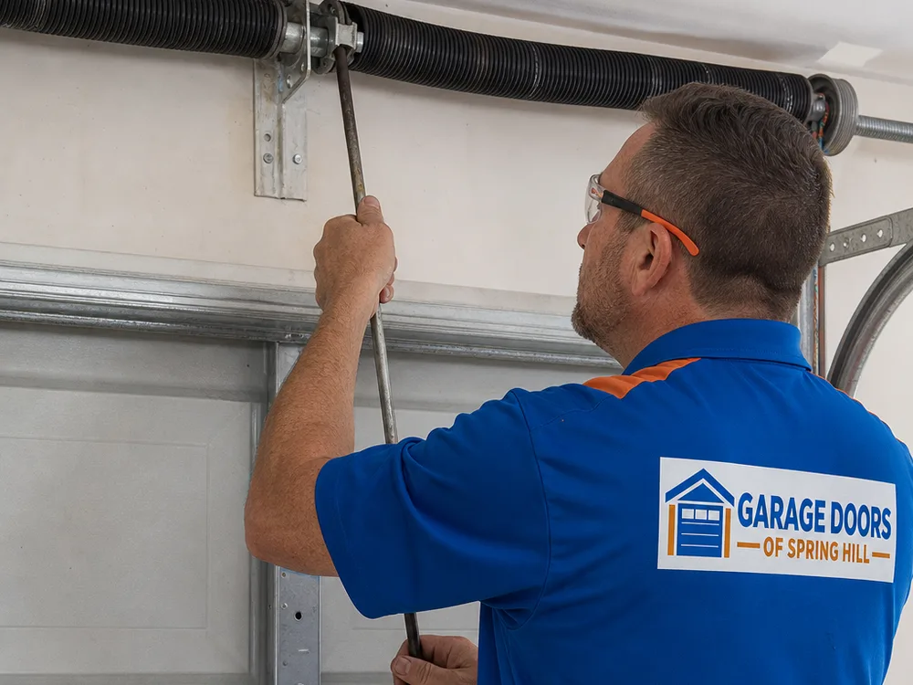 Contractor using winding bars at a torsion spring above a residential garage door